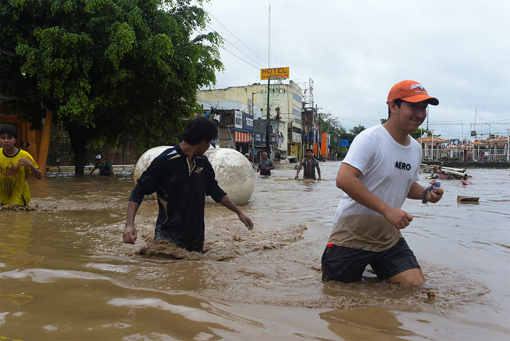 Gente camina por una calle inundada después de que las lluvias torrenciales desbordaran los ríos en Poza Rica.