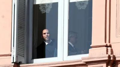Martín Guzmán se asoma desde una ventana de la Casa Rosada, al lado está Alberto Fernández, antes del anuncio por el cambio en Ganancias.